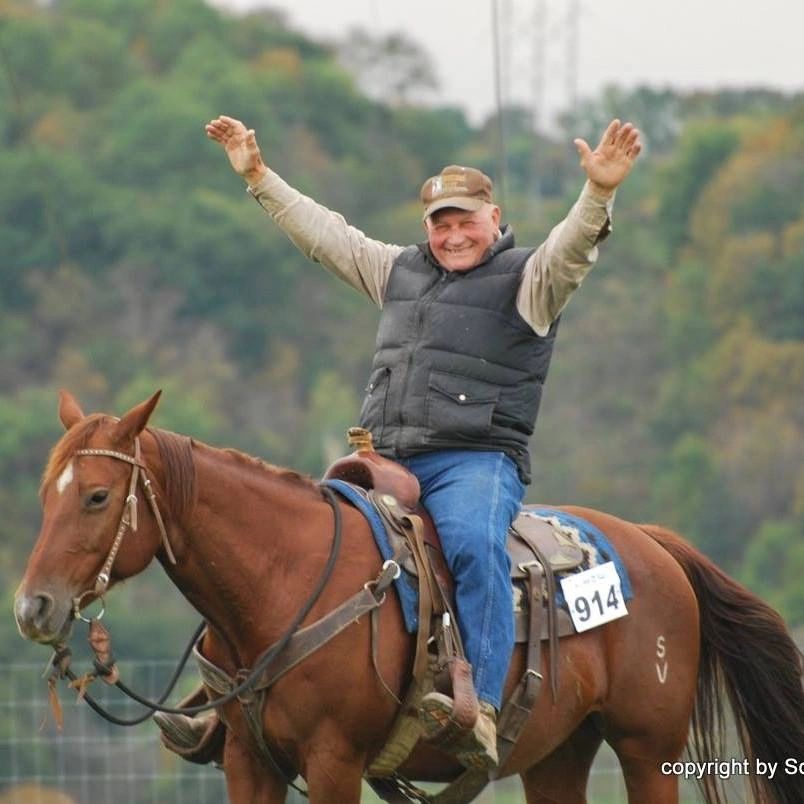 Lloyd Johanningmeier celebrating on horseback with his arms raised, wearing his competitor number bib